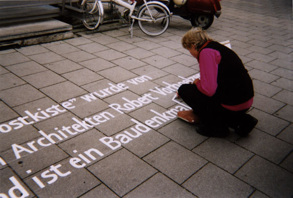 Irmgard Bauer bei der Beschriftung eines Gehwegs mit  Text zu einem Baudenkmal